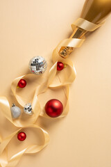 Vertical scene of festive decor featuring a champagne bottle, satin ribbon, silver disco balls and...