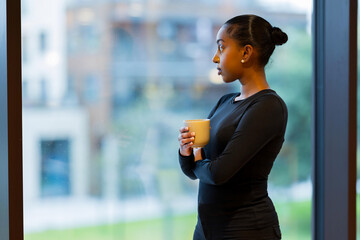 Woman holding coffee near a window