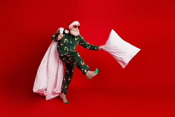 Santa in green pajama with red background engages pillow fight creating merry holiday energy for...