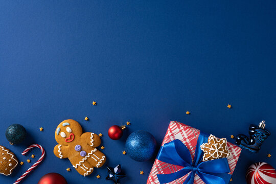 A cheerful holiday scene featuring gingerbread cookies, shiny ornaments, candy canes, and neatly wrapped presents with blue ribbon - Powered by Adobe