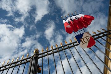 Flags of France fly at the Prefecture, catching the sunlight against a backdrop of clouds. The...