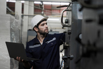 A man in a blue shirt and a white hat is looking at a laptop