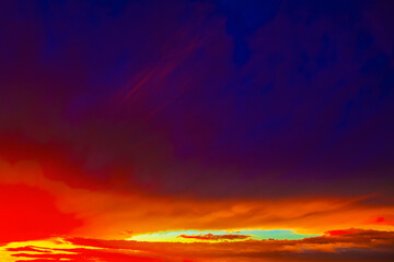 Intense sunset against deep indigo sky. Wispy clouds drift through gradient sky, capturing drama of vivid sunset or sunrise. Fiery blaze across the horizon, fading into deep purples and blues above 