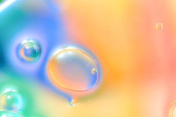 Macro image shows transparent soap-like bubbles in blue, green, peach tones floating in blended liquid. Smooth transitions, high detail, vivid colors create a dreamy abstract effect with copy space