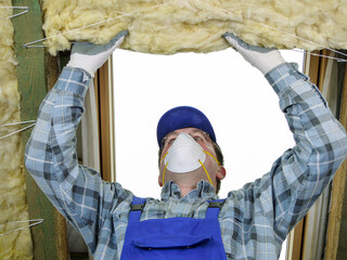 Worker thermally insulating a house attic using mineral wool