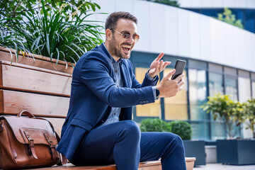 Happy smiling businessman making video call with his client via mobile phone. Business, lifestyle concept