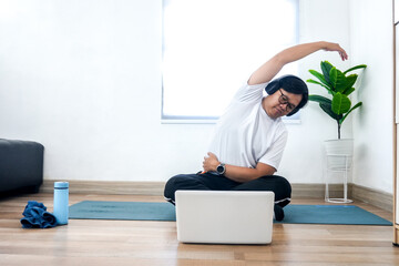 Young Asian Male Enjoys Stretching During Online Fitness Class