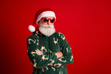 Festive Santa style man in green reindeer sweater with red sunglasses posed confidently against...