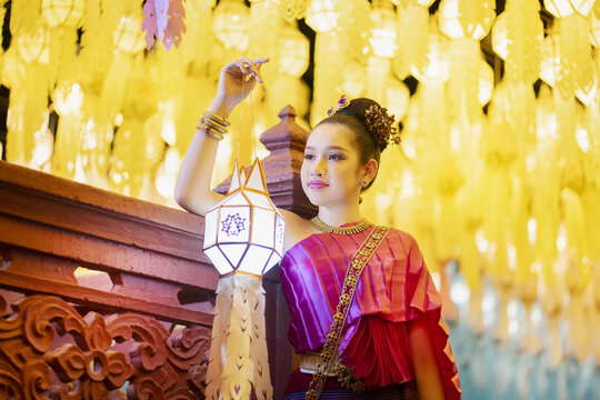 Traditional Thai woman in vibrant pink attire holding lantern, Hundred Thousand Lanterns Festival at Lamphun