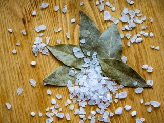 Dried bay leaves and sea salt on a wooden surface 