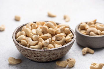 Dry cashew nuts in bowl on grey concrete table background, healthy vegan snack food