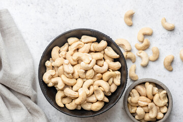 Dry cashew nuts in bowl on grey concrete table background, healthy vegan snack food