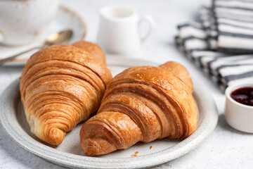 Closeup view two french flaky croissants served on a plate with cup of coffee. Delicious breakfast or coffee break meal
