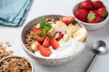 Healthy diet fitness meal: bowl of plain greek yogurt, topping granola strawberries banana