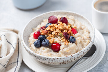 Healthy breakfast meal: oatmeal porridge with cranberries, blueberries and crunchy nutty granola topping