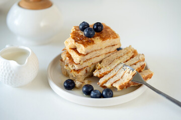 Stack of oat pancakes with blueberries cut in halves, healthy vegetarian breakfast meal