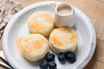 Syrniki, cottage cheese fritters served with blueberries, cream on a plate. Top view. Healthy breakfast meal