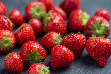 Delicious strawberries on a black slate background, closeup view