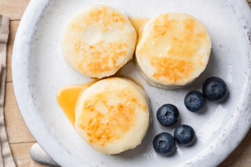 Syrniki, cottage cheese fritters served with blueberries, cream on a plate. Top view. Healthy breakfast meal
