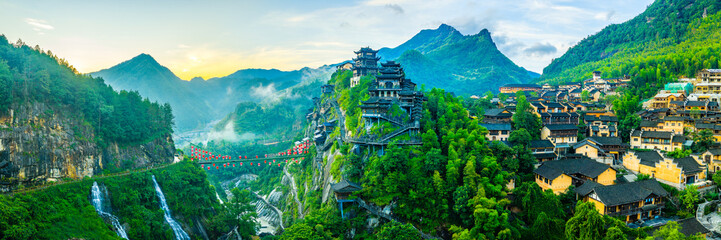 Beautiful ancient village with traditional wooden buildings on the green mountain at sunrise in Jiangxi, China.