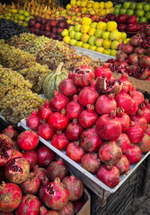 Fresh pomegranates on market stall. Vibrant red fruits displayed for sale at local farmers market. Healthy food and organic produce concept.