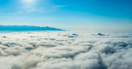 Magnificent sea of clouds and mountain scenery with a bright sun in the blue sky