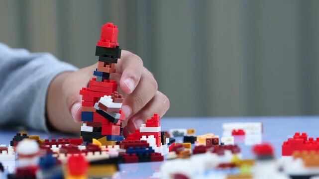 Children hands play with colorful lego blocks on white table.
