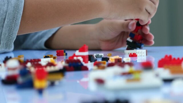 Children hands play with colorful blocks on white table.