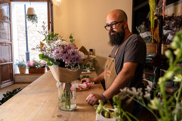 Florist arranging fresh flowers in small business shop