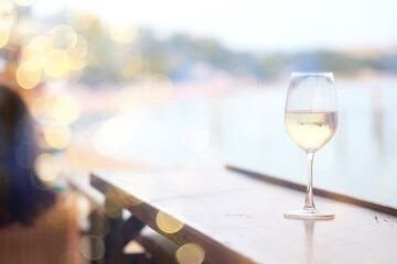 a glass of white wine, a background under the summer sun, a bokeh and sun glare, a blurred abstract background