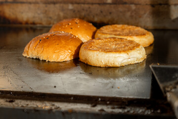 Burger buns being toasted on a flat griddle