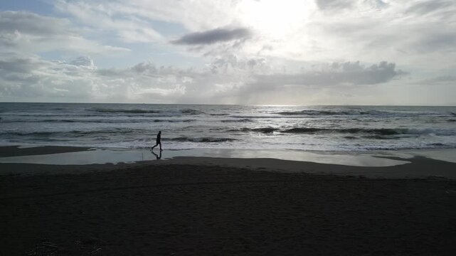drone, vista su uomo che corre sulla spiaggia (jogging)