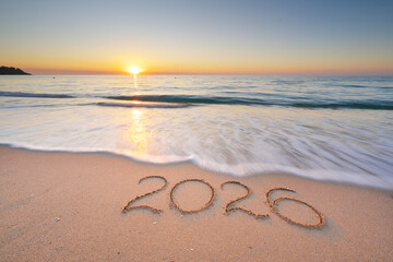 2026 text symbol of new year on the sea sand beach shore during sunset.