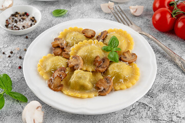 Tradition homemade Italian ravioli pasta with ricotta, mushrooms and parmesan cheese in a white plate on a concrete background. Top view.