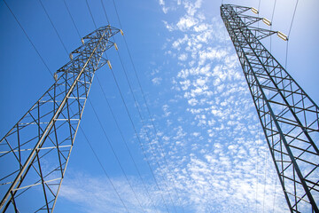 High voltage pylons against the blue sky and white clouds.