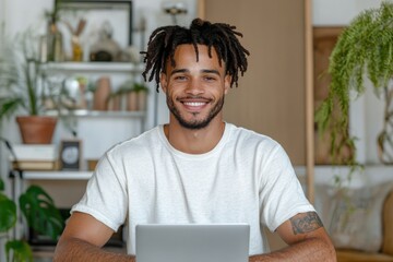 smiling african american freelancer with dreadlocks using laptop at home