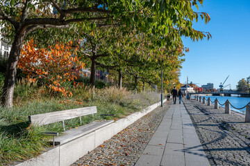 Unrecognizable people walk along Motala Stream and Norrköping waterfront Saltängen during autumn. Norrköping is a historic industrial town in Sweden.