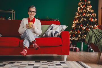 Senior woman enjoying coffee in a cozy home with Christmas decorations and festive spirit