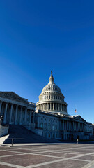 Naklejka premium Capitol building in Washington DC with dome and steps under clear blue sky in USA