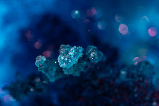 Blue crystal cluster with glittering highlights against a deep cyan backdrop; dreamy bokeh circles glow around the subject; abstract macro with selective focus and copy space.