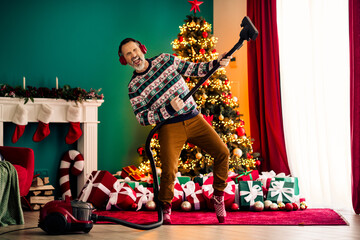 Elderly man enjoying festive Christmas cleaning session with vacuum cleaner near decorated tree and...