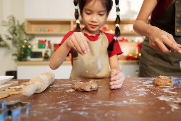 Creative Baking. Girl sprinkling flour while making cookies with mother.