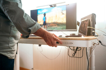Man raising standing desk in bright office.