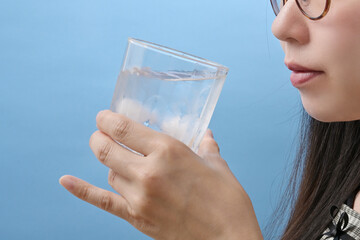 コップに注いだ水とグラスを持つ若い日本人女性