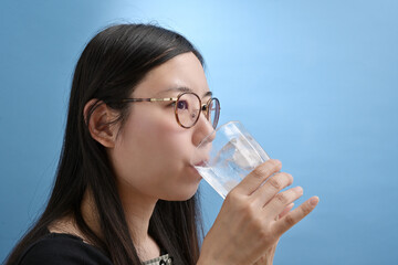 コップに注いだ水を飲む若い日本人女性