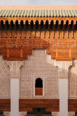 Traditional Moroccan roofline with ornate eaves and a small window opening, rich in earthy brown-red hues and historic craftsmanship.