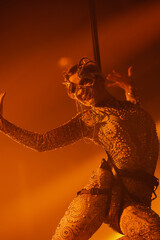 Female aerialist in a body harness performs midair with an ornate mask and jeweled bodysuit,...
