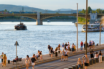 Budapest riverside view with walking people, bridge and vintage boat