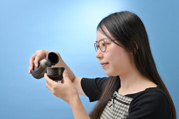 徳利から酒を注ぐ若い日本人女性