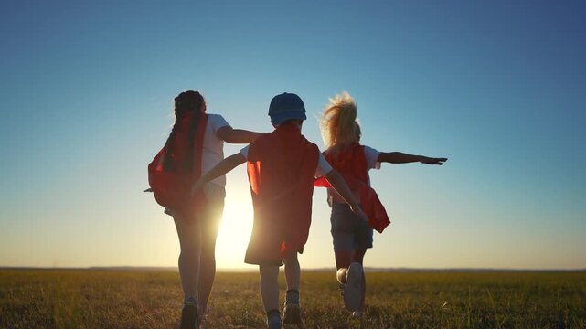 A group of kids are running around with superheroes. Hero super child concept. Group of lifestyle children running together, silhouette of. superheroes. A group of kids run together like superheroes.